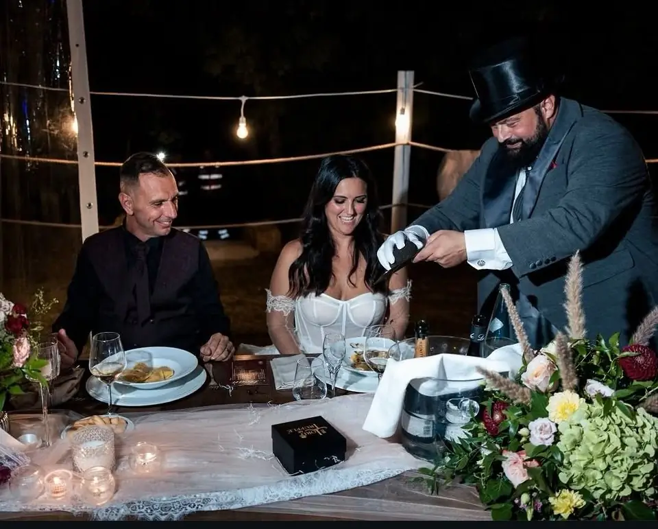 Gli sposi al tavolo, di sera, mentre il Lord lamella il Tartufo sul Raviolo of Love